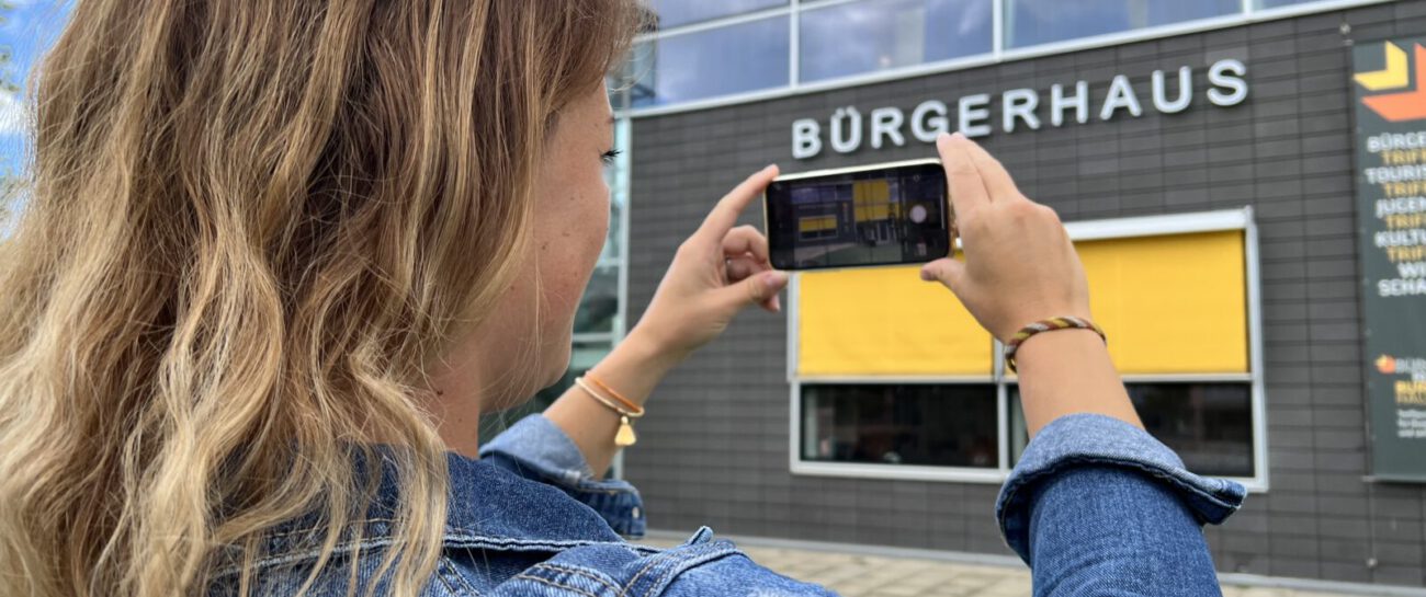 Frau beim Fotografieren des Bürgerhauses © Stadt Burghausen