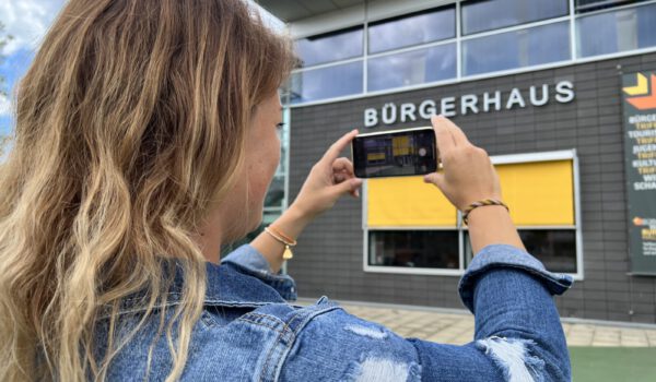 Frau beim Fotografieren des Bürgerhauses © Stadt Burghausen