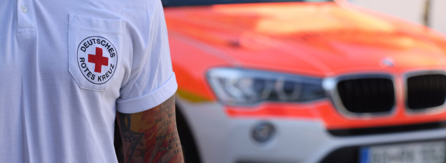 Sanitäter des Deutschen Roten Kreuzes mit Notarztwagen im Hintergrund © Gerhard Nixdorf