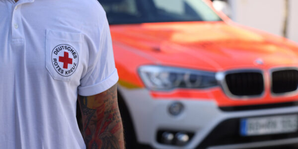 Sanitäter des Deutschen Roten Kreuzes mit Notarztwagen im Hintergrund © Gerhard Nixdorf
