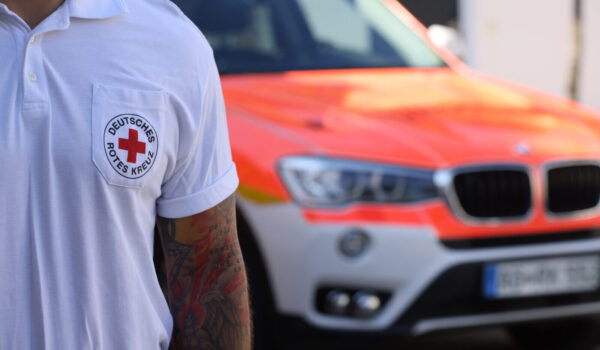 Sanitäter des Deutschen Roten Kreuzes mit Notarztwagen im Hintergrund © Gerhard Nixdorf