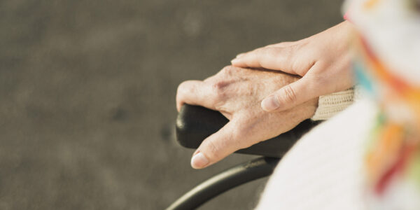 Hand hält Hand einer älteren Person im Rollstuhl © Westend61 / Uwe Umstätter