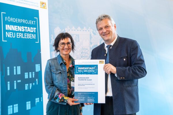 Sigrid Resch, GF der Burghauser Touristik, nahm den Förderbescheid „Innenstadt neu erleben!“ für die Nacht der Straßenkünstler von Staatssekretär Roland Weigert entgegen.