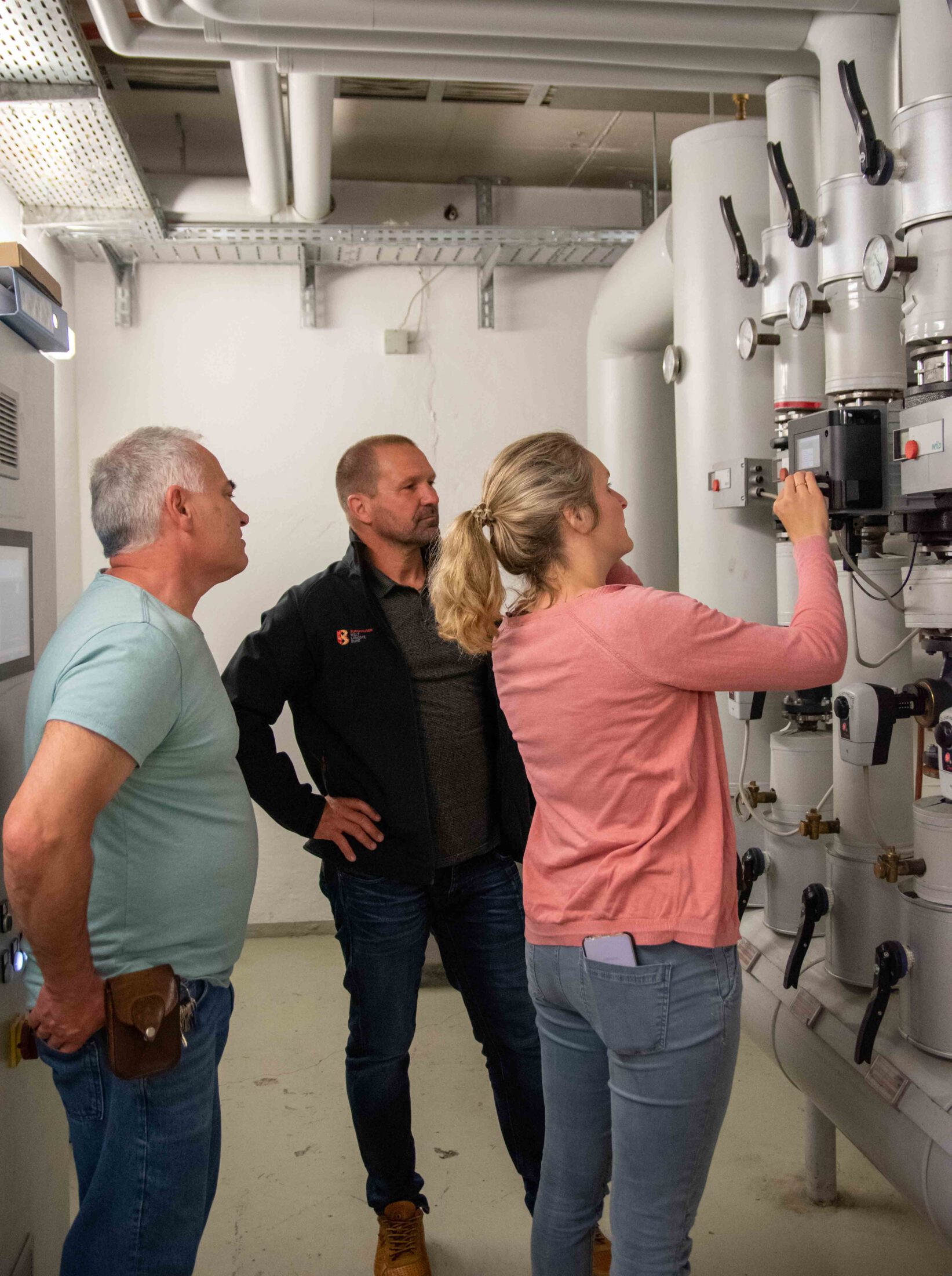 Klimaschutzmanagerin Verena Steiner mit Michael Madl (mitte) vom Gebäudemanagement und Thomas Lanner (links), Hausmeister der Franz-Xaver-Gruber-Schule, bei der Kontrolle im Heizungskeller © Stadt Burghausen/ebh