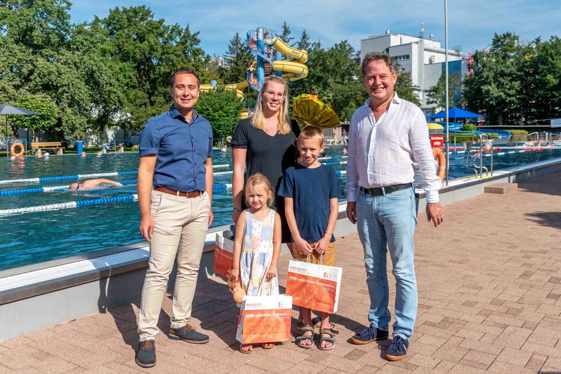 Familie Reichardt waren die 100.000sten Badegäste in der Freibad-Saison 2023. Erster Bürgermeister Florian Schneider (r.) und kaufmännischer Bäderleiter Stefan Sajdak (l.) überraschten die Familie mit einer kleinen Ehrung © Stadt Burghausen / ebh