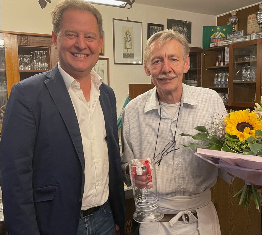 Erster Bürgermeister Florian Schneider überreicht am 3. Juni 2024 Manfred Jost zum Abschied einen Glas-Bierkrug von Glaskünstler Sigi Franz. Nach mehr als 50 Jahren sind im Wirtshaus St. Johann jetzt bis auf Weiteres die Lichter aus. Fotocredit: Stadt Burghausen
