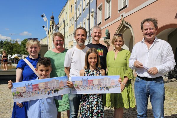 V. l. n. r.: Gertrud Stadler, Rektorin der Hans-Kammerer-Schule, Zweitklässler Rafael, Margit Burgstaller, Rektorin der Johannes-Hess-Schule, Dritter Bürgermeister Stefan Angstl, Viertklässlerin Heidi, Grafiker Frans Stummer, Julia Schumergruber, Rektorin der Hans-Stethaimer-Schule und Erster Bürgermeister Florian Schneider mit dem Wimmelbild des Burghauser Stadtplatzes. © Stadt Burghausen / ebh