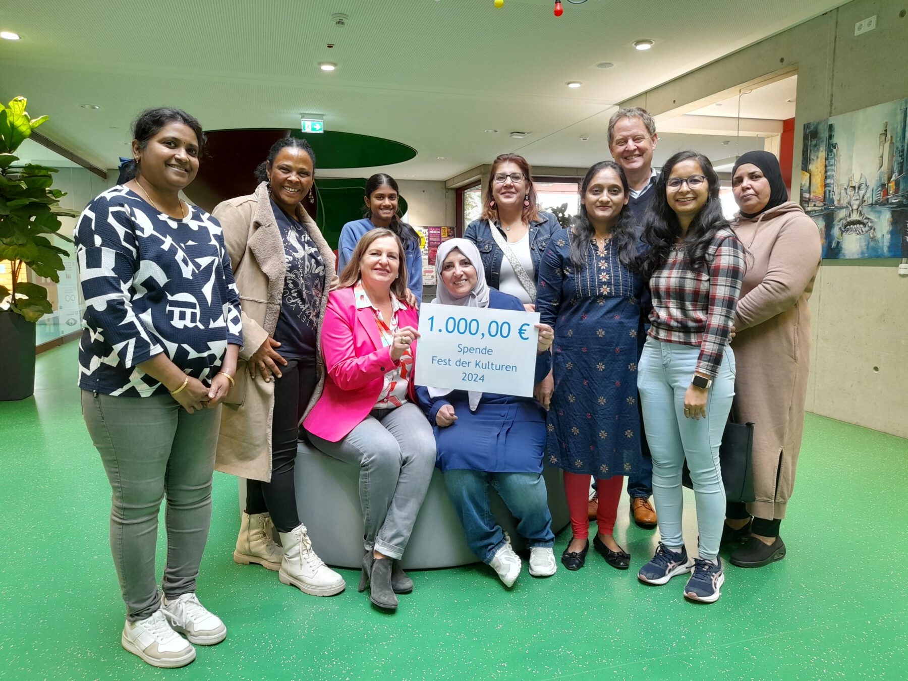 Foto: Acht engagierte Bürgerinnen und Bürger übergeben eine Spende von 1.000 Euro an Sozialamtsleiterin Elisabeth Rummert (sitzend links) und Ersten Bürgermeister Florian Schneider: Swathi Kotha, Mery Teshome, Yashaswi Kotha, Haifa Ragab, Rabiaa Mohammed, Kinjal Bhayani, Jahanvi Modi und Sabah Turkmane. Fotocredit: Stadt Burghausen / Haus der Familie