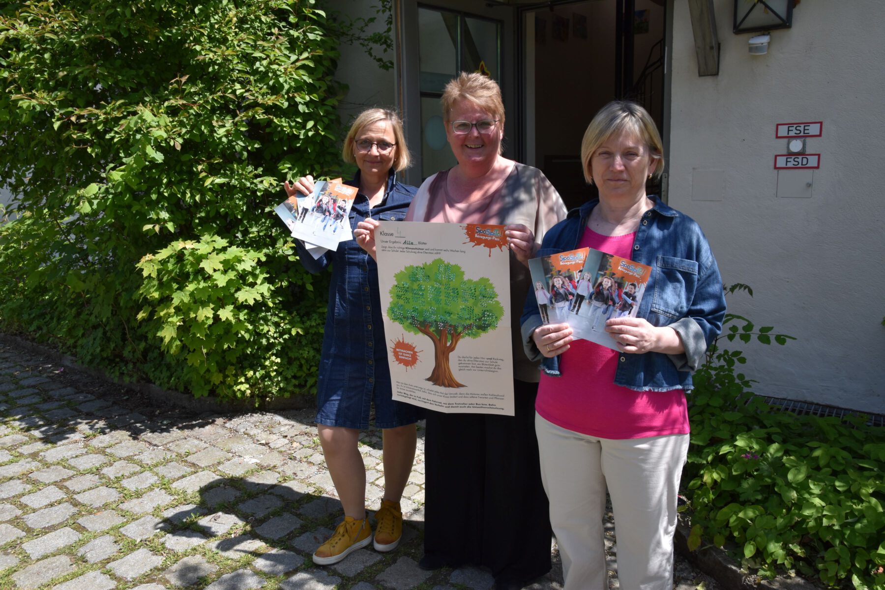 Die drei Leiterinnen der Burghauser Grundschulen (v.l.): Julia Schumergruber (Hans-Stethaimer-Grundschule), Margit Burgstaller (Johannes-Hess-Grundschule) und Gertrud Stadler (Hans-Kammerer-Schule) mit den SpoSpiTo-Materilalien, die an die Schüler ausgegeben wurden, vor der aktuellen Ausweich-Schulstätte der Hans-Stethaimer-Schule auf der Burg.