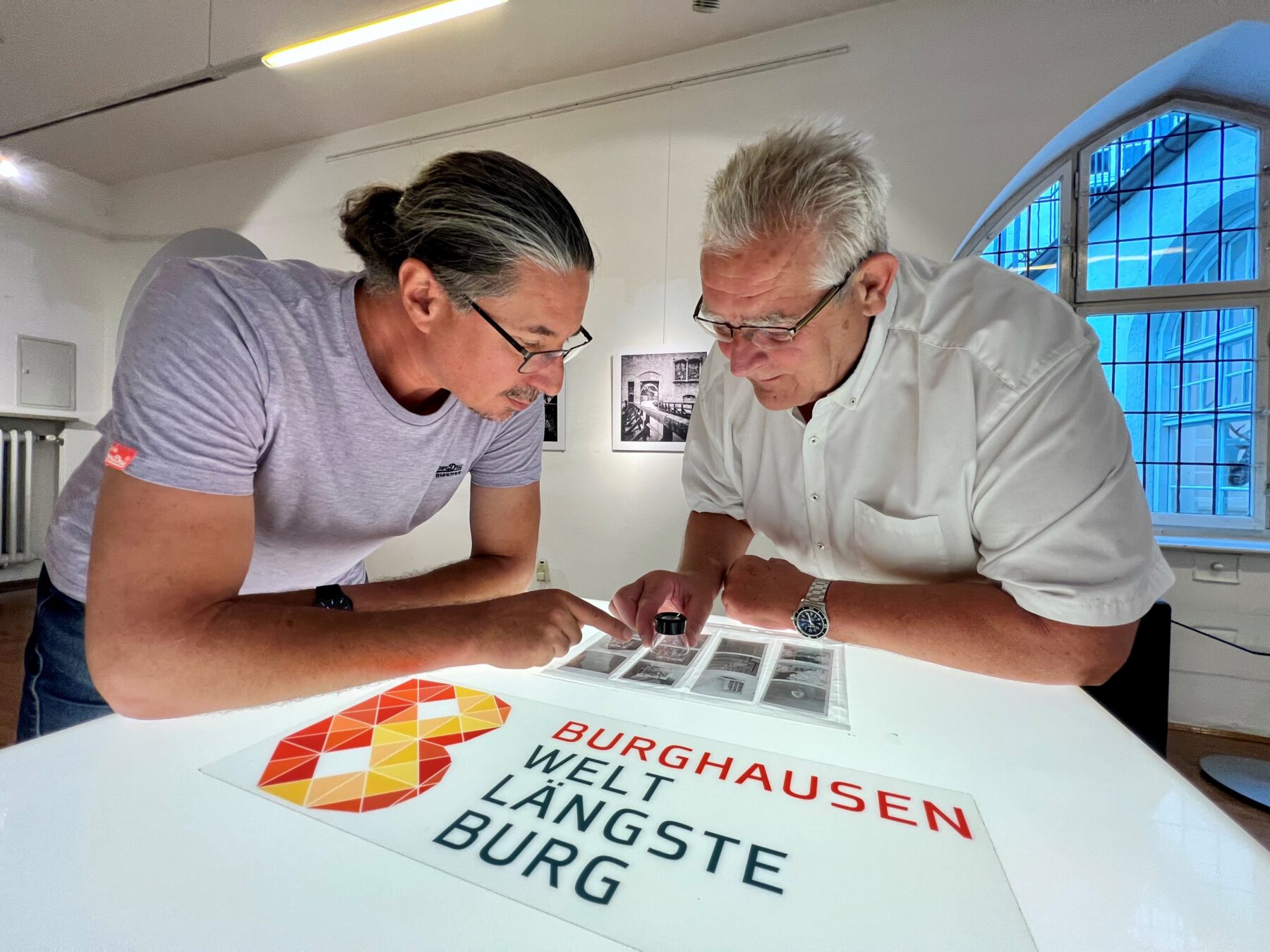Zweiter Bürgermeister Norbert Stranzinger in der Ausstellung mit dem Fotografen Daniel Mittermeier aus München  Er Negative mitgebracht, die mit einer Lupe anzuschauen sind  Fotocredit: Stadt Burghausen / Königseder