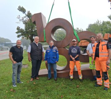 Für vier Wochen wird die 1000 nun an der Hauptpforte von WACKER stehen – dorthin begleiteten sie (v.l.) Bauhofleiter Peter Schweikl, Zweiter Bürgermeister Norbert Stranzinger, Michael Strasser (WACKER) sowie das Transportteam vom städtischen Bauhof. Fotocredit: Stadt Burghausen/tg
