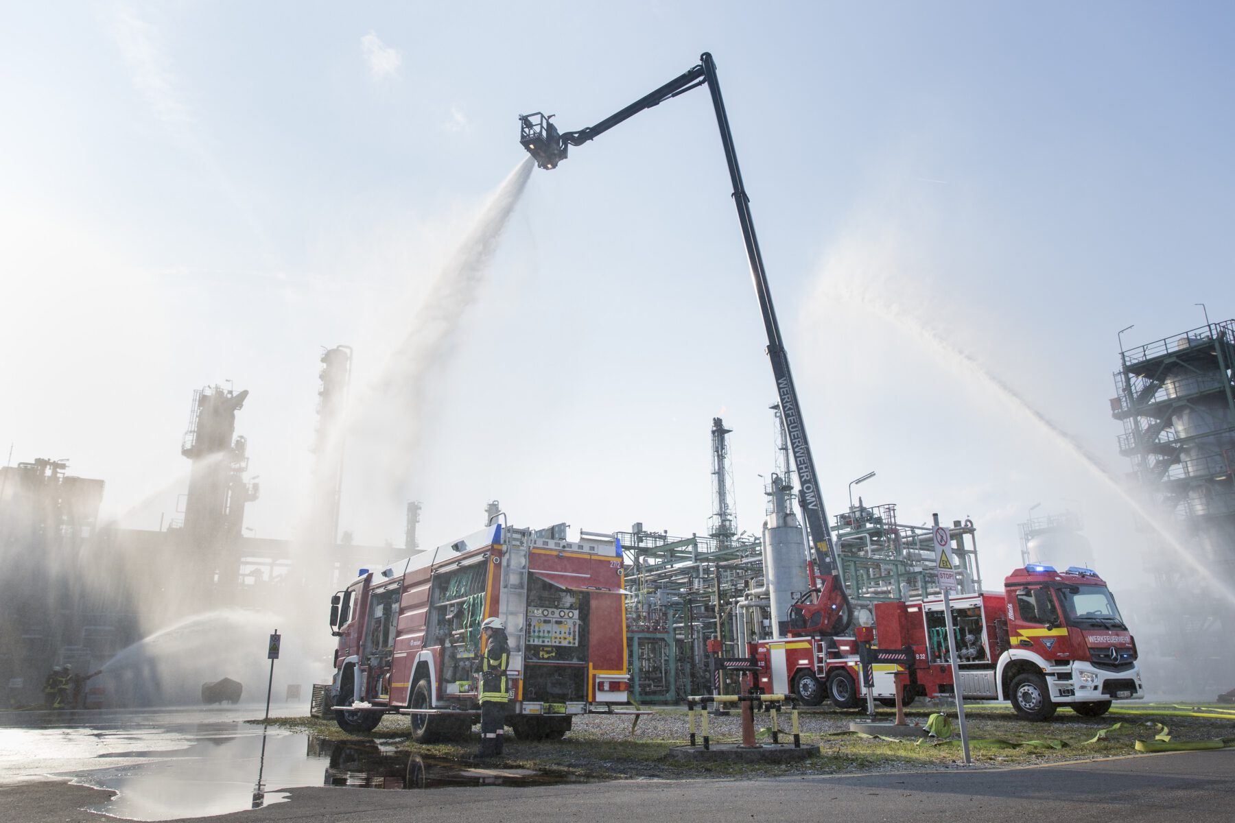 Zwei Feuerwehrfahrzeuge führen eine Löschübung in einer chemischen Produktionsanlage durch.