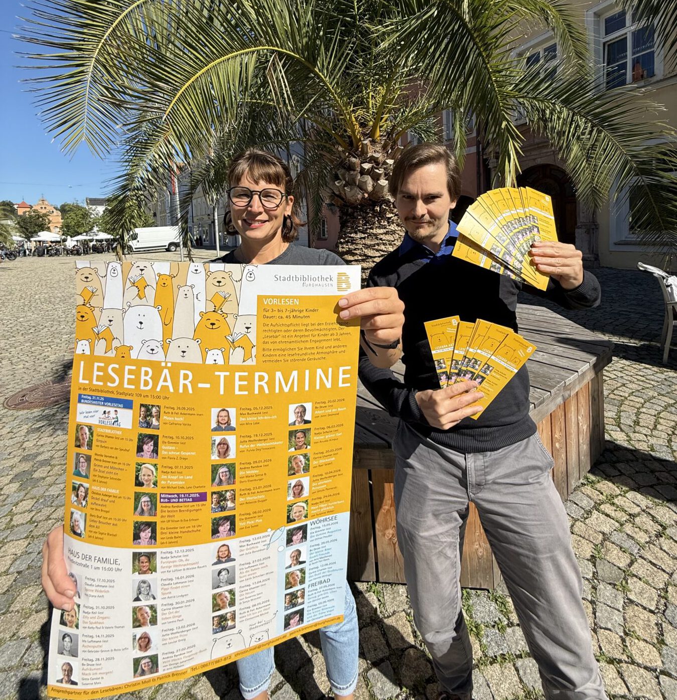 Die Leiterin der Stadtbibliothek Christin Moll und Mitarbeiter Patrick Brenner zeigen das neue Programm „Lesebär aktuell“ 2025 / 2026. Fotocredit: Stadt Burghausen