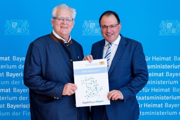 20260709_103448_Gigabit-Siegel_GF2_0382_quer Für Burghausen nahm Zweiter Bürgermeister Norbert Stranzinger (l.) die Urkunde von Finanz- und Heimatstaatssekretär Martin Schöffel entgegen. Fotocredit: Florian Graser StMFH