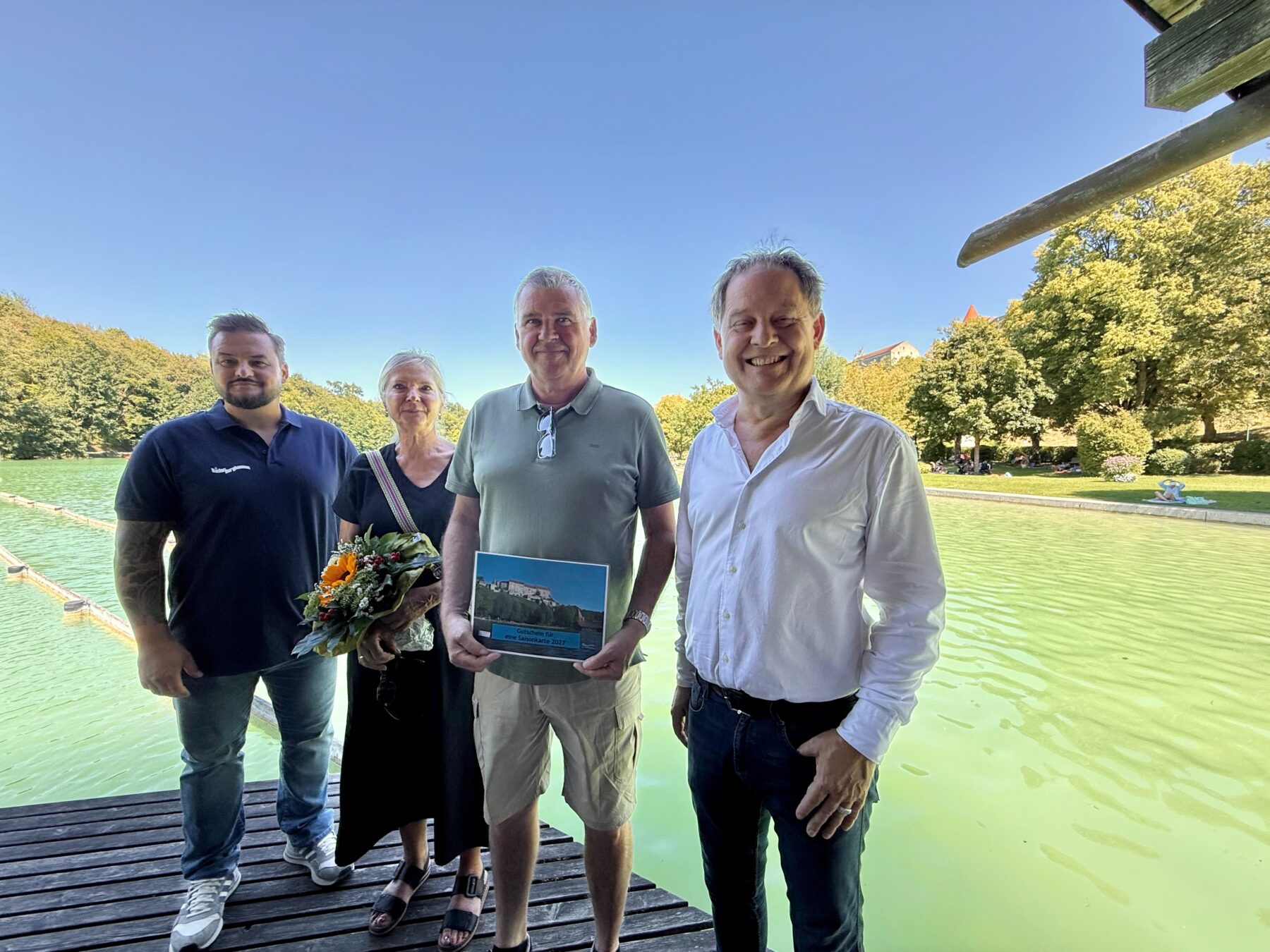 Erster Bürgermeister Florian Schneider und Bäderleiter Florian Moser begrüßten das Ehepaar Rosmarie und Richard Siegerd aus Haiming als 100 000 Badegäste  Das Ehepaar ist Stammgast und besucht den See mindestens vier Mal pro Woche  „Wir schätzen die sehr gute Wasserqualität und die natürliche Beschattung  Das Flair ist einzigartig und wenn wir am Vormittag da sind ist es auch noch schön ruhig“, so die Siegerds  Als kleine Aufmerksamkeit überreicht das Stadtoberhaupt Blumen und eine Saisonkarte für das nächste Jahr 